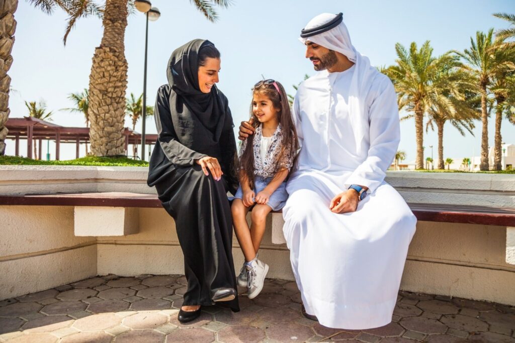 दुबई के पार्क में बेटी के साथ बैठा अमीराती परिवार आत्मविश्वासी बच्चे लचीले पेरेंटिंग भावनात्मक सचेत
