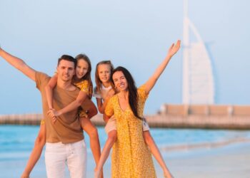 一家人在海滩上，背景是迪拜的帆船酒店，自信的孩子，坚韧的育儿，情感专注