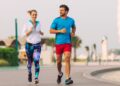Man and woman running on path near Burj Al Arab outdoor fitness training temperature parks morning
