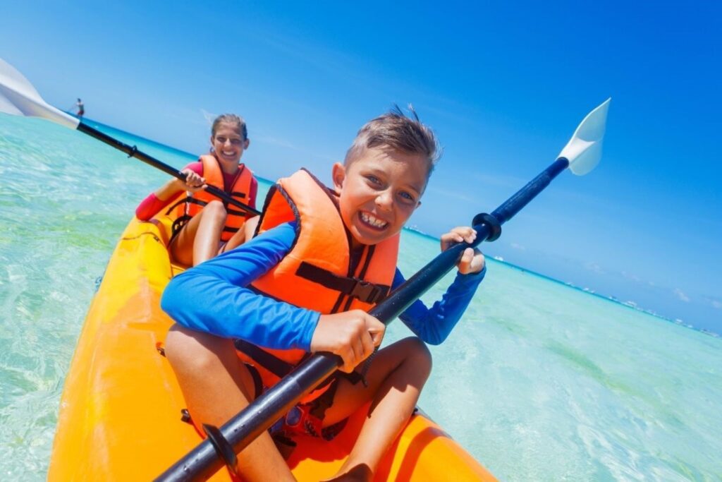 一家人在迪拜乐园（La Mer Dubai）享受皮划艇和桨板海滩运动，代表着适合所有年龄段的无障碍水上活动，条件平静，有专业指导。