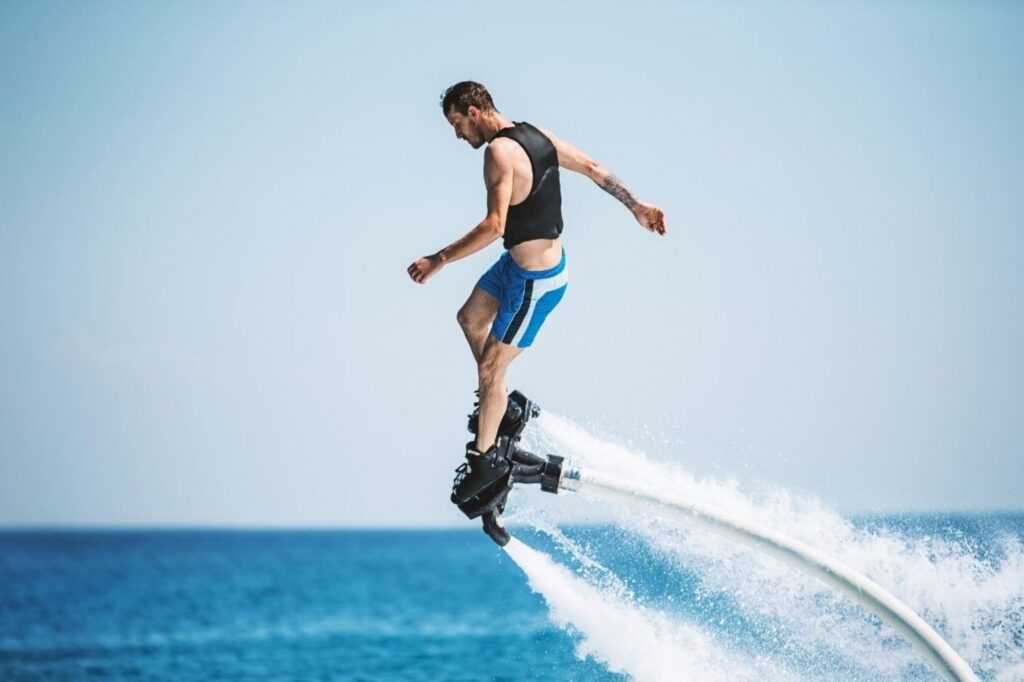 运动员在迪拜阿拉伯塔附近进行飞板海滩运动，展示通过强大喷气背包技术将骑手推向阿拉伯湾上空的极限水上活动