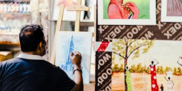 A designer works at a wooden table inside a warehouse studio that forms part of the Dubai design scene at Alserkal Avenue