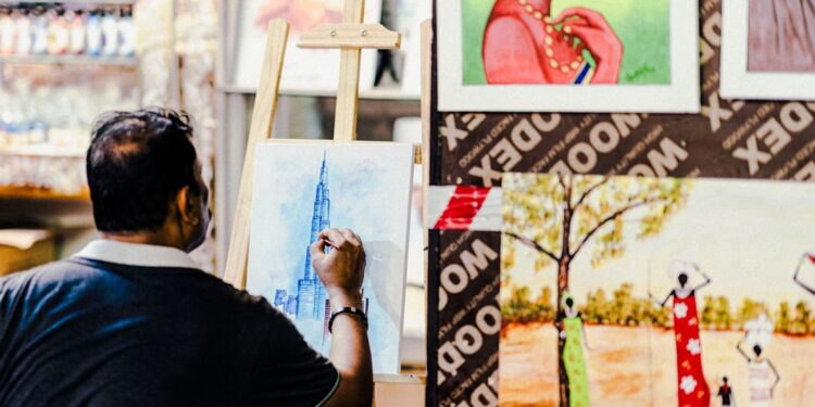 A designer works at a wooden table inside a warehouse studio that forms part of the Dubai design scene at Alserkal Avenue