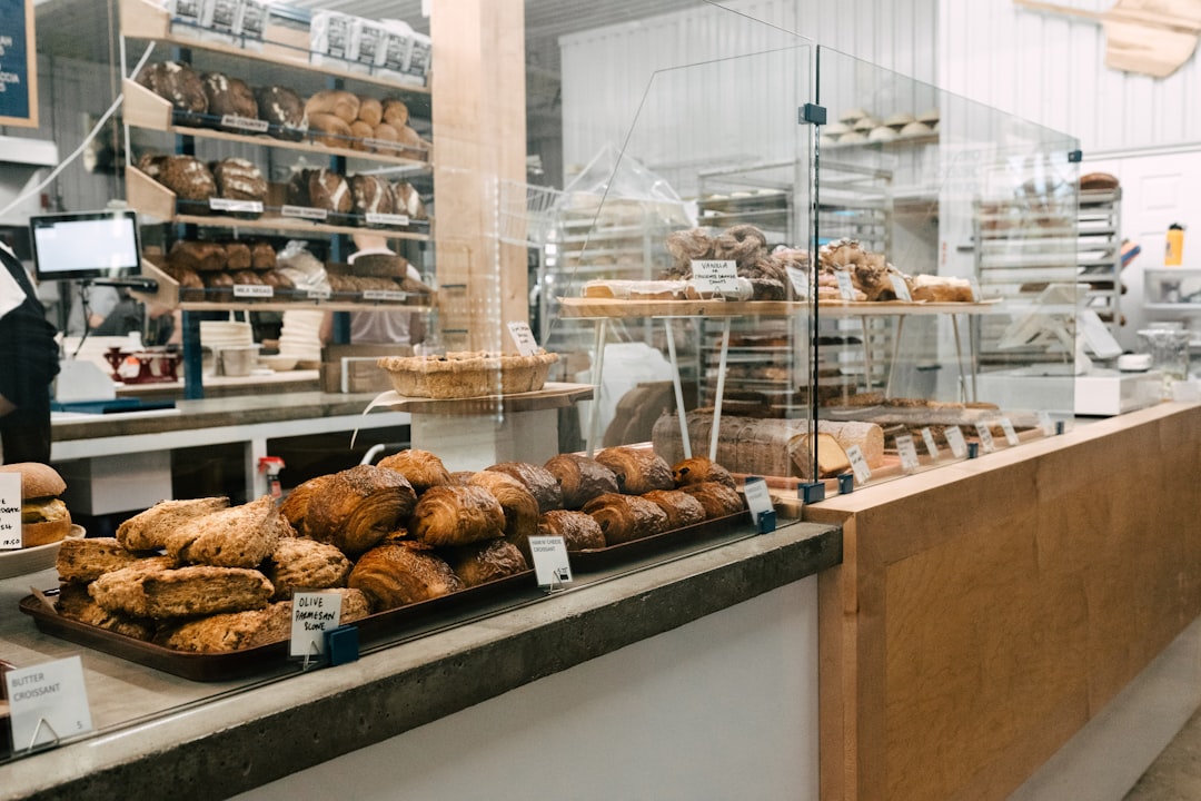 A barista handing a plate of pastries to a customer at a gluten-free bakeries cafe in Dubai, with light filling the space.