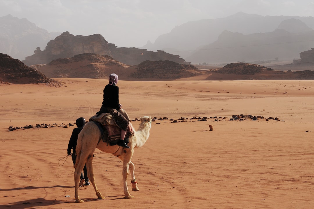 A local guide leading visitors on a camel ride as part of a desert escape near Dubai at golden hour