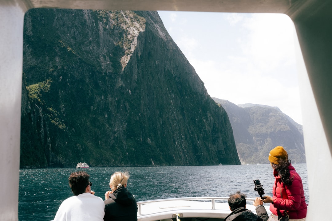 A traveller standing on a traditional dhow boat sailing through the dramatic fjords of Musandam on a day trip from Dubai