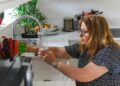 A woman inspecting a kitchen tap in a modern Dubai home to reduce household water use