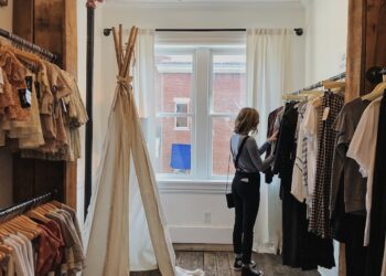 A woman browses slow fashion garments at an ethical boutique in Dubai, examining fabric quality with care.