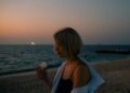 woman-walking-dubai-beach-unsplash - DUBAIwebzine A visitor walks along Dubai Creek during the Hijri New Year long weekend, with the water behind her.
