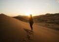 A traveller watching the sunrise over golden dunes during a summer desert escape near Dubai