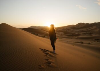 A traveller watching the sunrise over golden dunes during a summer desert escape near Dubai