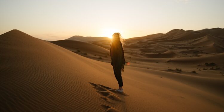 A traveller watching the sunrise over golden dunes during a summer desert escape near Dubai