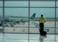 A traveler checking the departures board at Dubai International Airport before choosing summer flights to Europe