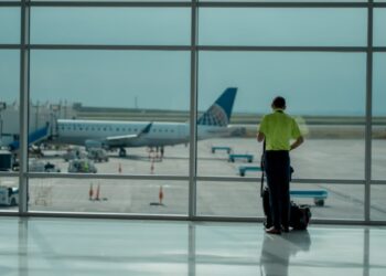 A traveler checking the departures board at Dubai International Airport before choosing summer flights to Europe