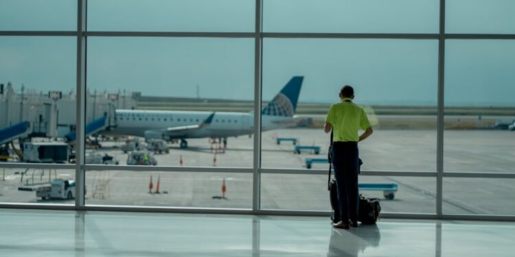 A traveler checking the departures board at Dubai International Airport before choosing summer flights to Europe