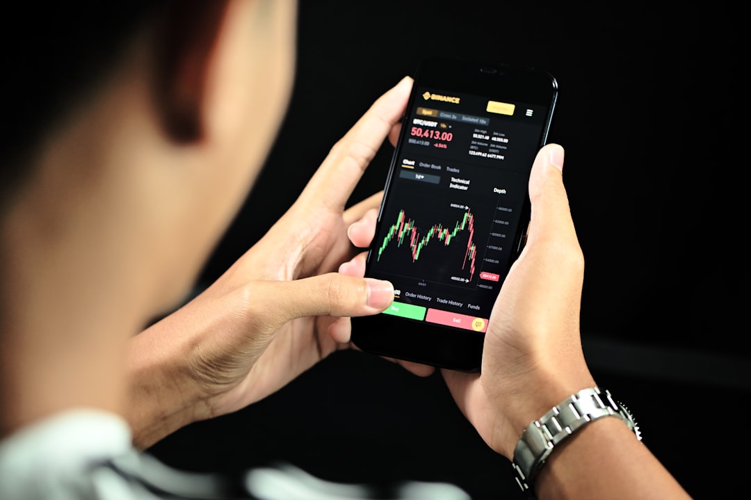 A professional investor monitors digital gold trading data on a smartphone near Dubai's gold souk, bridging commodity markets