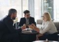 businessmen-meeting-unsplash - DUBAIwebzine A businesswoman reviews investment data inside the DIFC Dubai financial centre, with the skyline visible through the window.