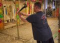 A focused player steps up to the oche at a Dubai darts tournament, with a cheering crowd visible behind him