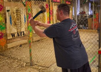 A focused player steps up to the oche at a Dubai darts tournament, with a cheering crowd visible behind him
