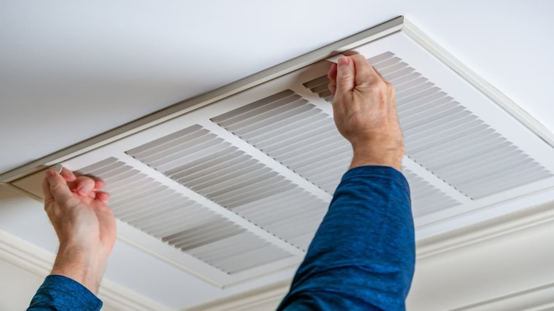A person removing and cleaning an air conditioning filter to keep their cool home running efficiently in Dubai