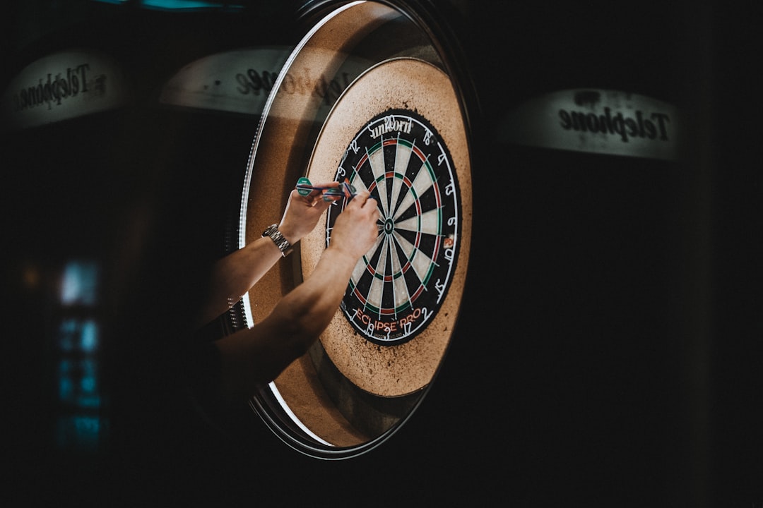 A professional player walks onto the stage under bright lights at a Dubai darts competition, ready to compete