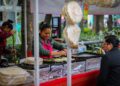 A vendor carefully wraps fresh shawarma at a busy street food stall in a Dubai corridor at night