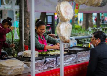 A vendor carefully wraps fresh shawarma at a busy street food stall in a Dubai corridor at night