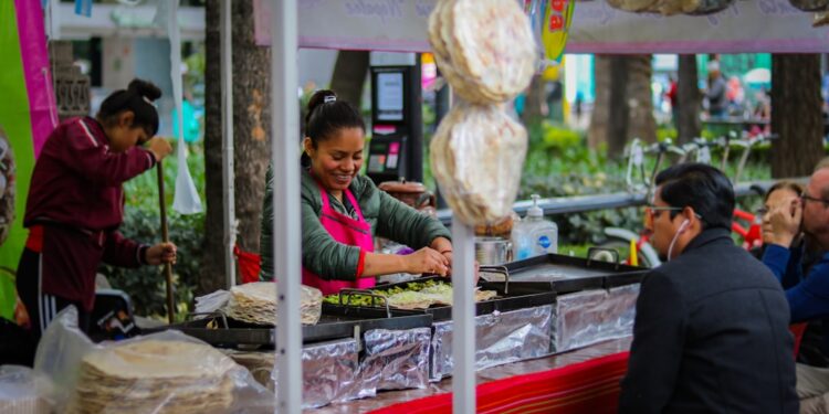 A vendor carefully wraps fresh shawarma at a busy street food stall in a Dubai corridor at night