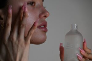 A woman applying Dubai skincare cream in a bright modern bathroom, looking into a mirror with a calm expression
