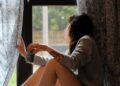 A woman closing blackout curtains in a bright Dubai apartment to maintain a cool home during summer