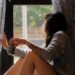 A woman closing blackout curtains in a bright Dubai apartment to maintain a cool home during summer