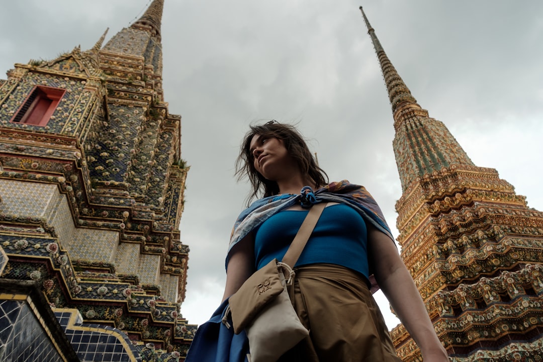 A woman exploring a Bangkok temple after taking summer flights from Dubai to Southeast Asia