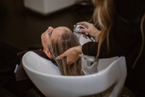 A stylist applying professional hair treatments to a client's hair in a Dubai salon, protecting against humidity and frizz.