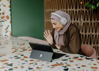 A digital nomad working at a bright coworking space in Dubai, with a laptop open and city views behind her
