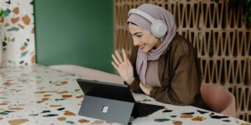 woman-laptop-working-in-a-cafe-dubai-coworking-unsplash - DUBAIwebzine A digital nomad working at a bright coworking space in Dubai, with a laptop open and city views behind her