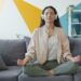 woman-meditating-indoors-apartment-unsplash - DUBAIwebzine A woman practising morning meditation in her Dubai apartment, protecting her mental health during the summer.