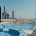 woman-relaxing-infinity-pool-dubai-skyline-unsplash - DUBAIwebzine A woman relaxes at the edge of one of Dubai's most stunning luxury pools with the city skyline behind her