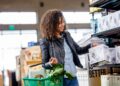 A woman filling her own glass jar at a zero waste grocery store bulk food station in Dubai