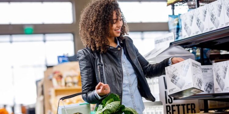 A woman filling her own glass jar at a zero waste grocery store bulk food station in Dubai
