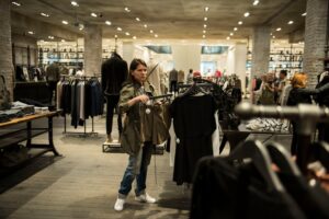 A woman browsing clothing rails at a preloved boutique, building a sustainable wardrobe in Dubai on a mid-range budget.