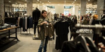 A woman browsing clothing rails at a preloved boutique, building a sustainable wardrobe in Dubai on a mid-range budget.