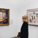 A visitor stands before a large canvas inside one of Dubai's air-conditioned art galleries during summer