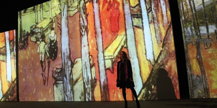woman-walking-digital-projection-museum-unsplash - DUBAIwebzine A woman walks through a glowing digital projection room at an immersive art experience inside a Dubai mall