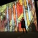 A woman walks through a glowing digital projection room at an immersive art experience inside a Dubai mall
