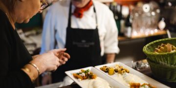 A chef presents a beautifully plated course to a seated guest as part of a summer menus Dubai tasting experience