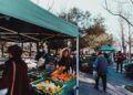 family-outdoor-food-market-weekend-unsplash - DUBAIwebzine A woman selects organic vegetables at a Dubai farmers markets stall, surrounded by colourful local produce