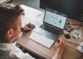 A focused professional searching for freelance clients on a laptop inside a modern Dubai coworking space