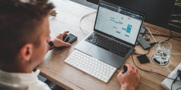 A focused professional searching for freelance clients on a laptop inside a modern Dubai coworking space