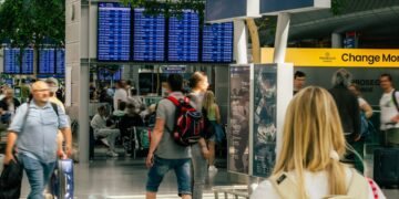 A smiling traveler checks her boarding pass at a Dubai transit hub departure gate, preparing for her connecting flight.