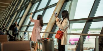 A traveler checking a boarding pass at a Dubai departure gate before flying one of the expanded Emirates routes